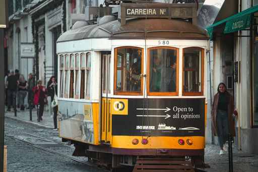 An antique street tram traveling along its tracks in a cityscape, Lisbon, Portugal