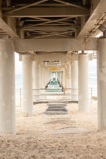 A vertical shot of a pier with columns near the sea during daytime