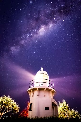 A vertical shot of a lighthouse under the beautiful Milky Way Galaxy