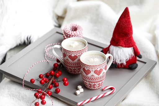 A Christmas set with two cups of hot chocolate, candy cane, holly inex and a Santa toy