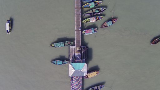 An aerial top view of many moored sailing boats lined up on the piers