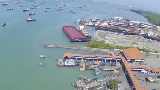 An aerial shot of many moored sailing boats lined up on the piers and a waterfront city