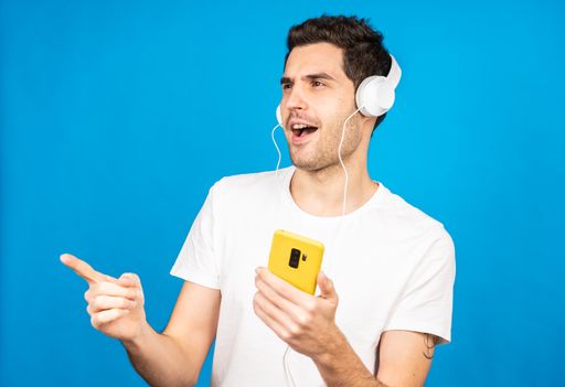 A handsome Caucasian man wearing headphones and listening to music - enjoying
