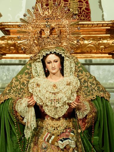 A vertical shot of a decorated church with the statue of Virgin Mary, crown on her head