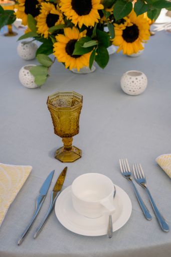 A vertical shot of sunflower decorations, cutlery, and a tea cup on a table