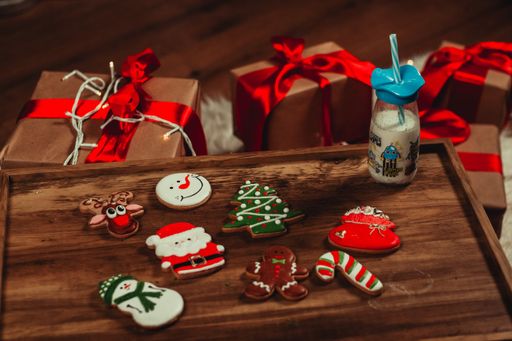 A high angle shot of gingerbread Christmas cookies with a bottle of milk on a wooden tray