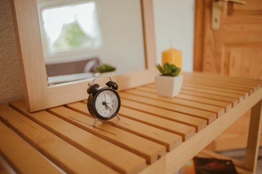 A selective focus shot of a black alarm clock on the wooden table