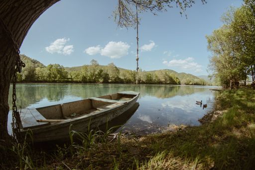 A closeup shot of an old boat parked on the river bank on a sunny day