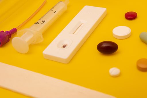A top view of syringe, pills, and a thermometer on yellow background