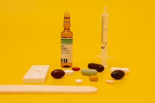 A top view of syringe, pills, and a thermometer on yellow background