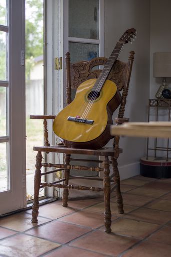 A vertical shot of a guitar on a wooden chair