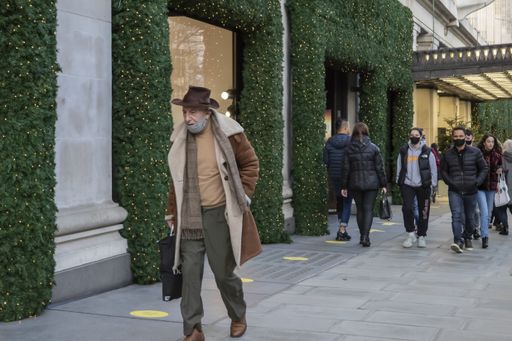London, England - December 17th 2020: Festive decoration on Oxford Street. People wearing face masks while walking on the pavement.