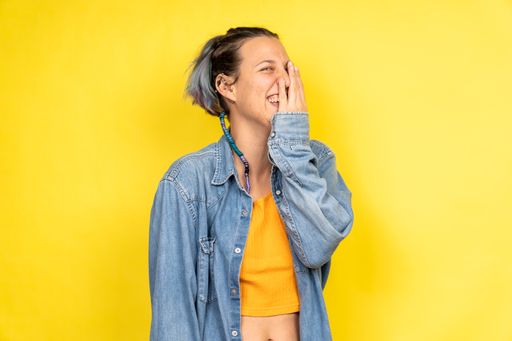 A pretty Caucasian woman laughing and covering her face with one hand - copy space