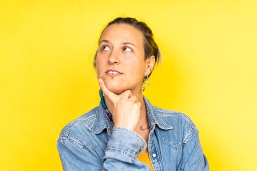 A pretty Caucasian woman posing with a thoughtful facial expression on a yellow background