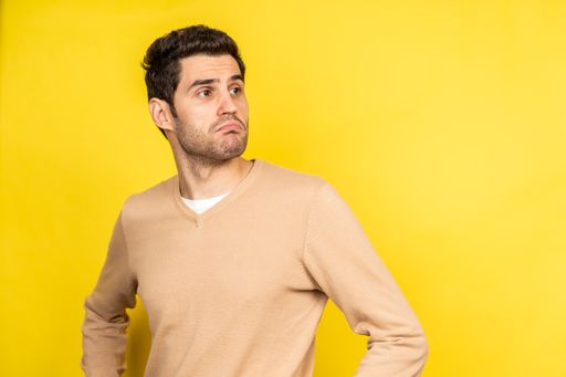 A handsome Caucasian posing with uncertainty on a yellow background - copy space