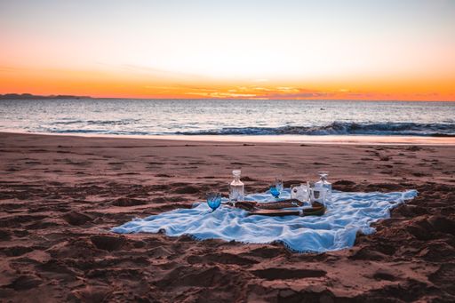 A closeup shot of a picnic on the seashore near the sea under a sunset sky