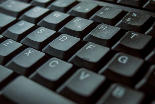 A selective focus shot of a black keyboard with white letters