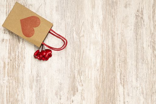 A cardboard bag and small red hearts on wooden background