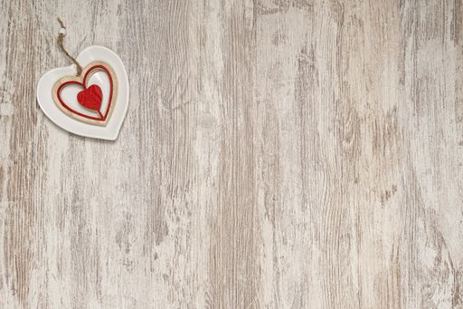 A top view of a white heart-shaped plate and small wooden heart on the wooden background
