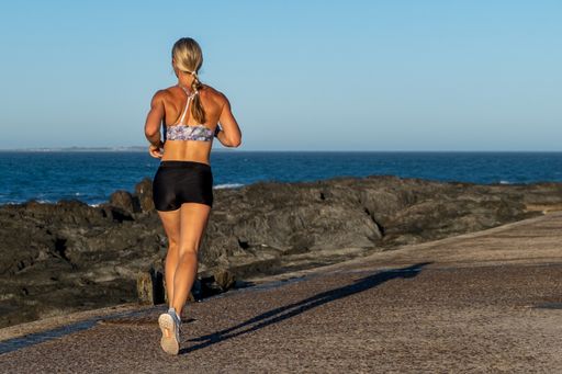 Blonde woman out on a jog in the early morning with the sea and rocks in the background