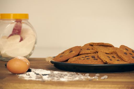 A closeup shot of a plate of chocolate chip cookies and eggs on the side