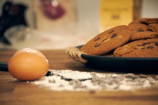 A closeup shot of a plate of chocolate chip cookies and eggs on the side