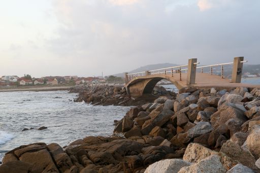 A beautiful shot of the rocky coast with a small bridge and with a lot of buildings