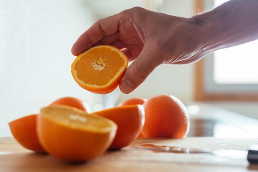 A man's hand picking a sliced orange from a kitchen counter - boosting immune system against COVID-1