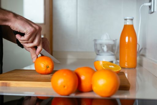 A man slicing oranges on a kitchen counter to make orange juice - boosting immune system against COVID-19