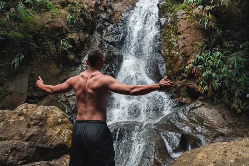 A young male admiring a beautiful waterfall on a daytime