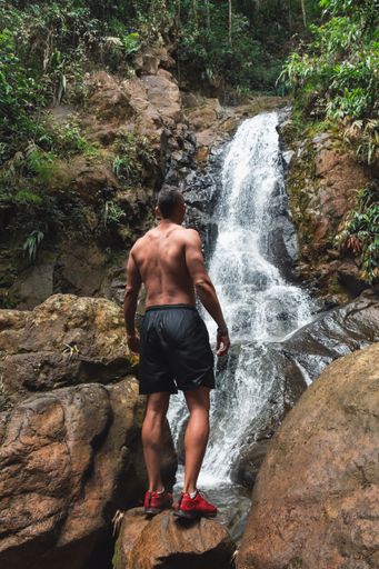 A young male looking at a beautiful waterfall on a daytime