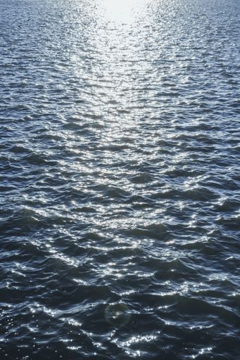 A vertical shot of seawater texture, sunlight reflecting on the surface