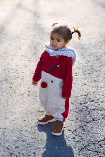 A shot of a cute little girl in Christmas clothes walking in a park