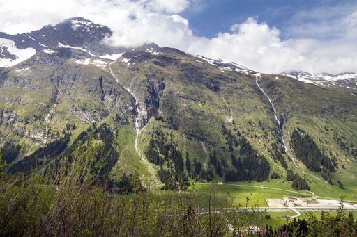 A snow-capped forested mountain under a beautiful cloudy sky