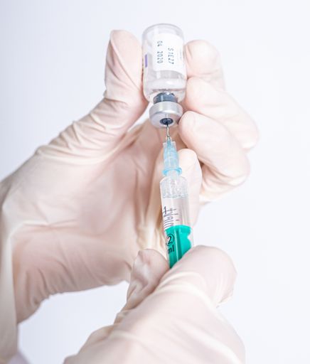 A selective focus shot of a hand holding an injection syringe with peptides