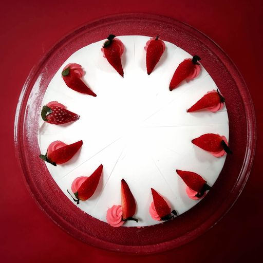 A top view of a cake with strawberry topping isolated on a red background