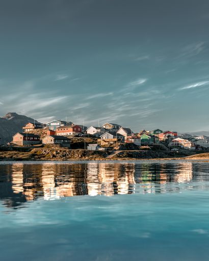 A vertical shot of colorful houses on a hill reflected on a frozen lake during the winter