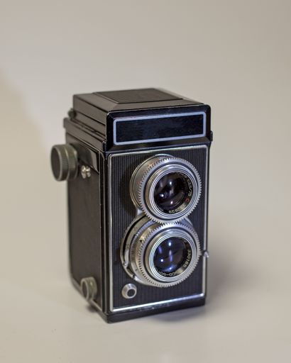 A vertical high angle shot of a vintage twin-lens camera on a white background