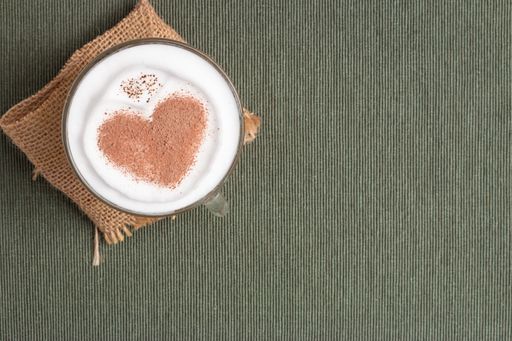 A top view of a table surface with a heart shaped latte and copyspace
