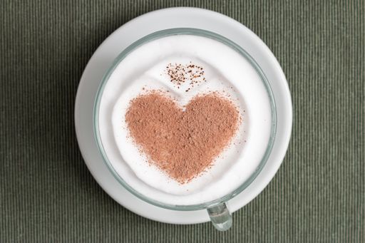A top view shot of a cappuccino cup with a heart shape on the surface on the gray background - the St. Valentine's day concept