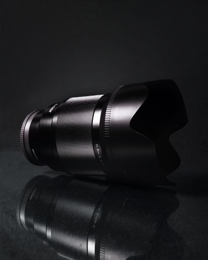 A vertical shot of a modern camera lens on a black background
