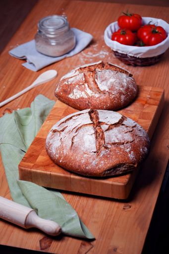 A vertical shot of freshly baked loves of sourdough bread on a wooden board