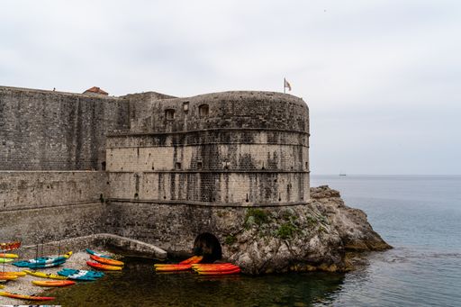 An aerial shot of boats near a castle on the seaside in Dubrovnik in Croatia