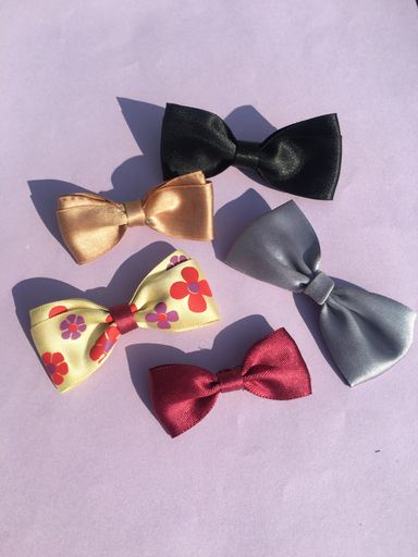 A top view of colorful satin ribbon bows with shadows on a light violet background