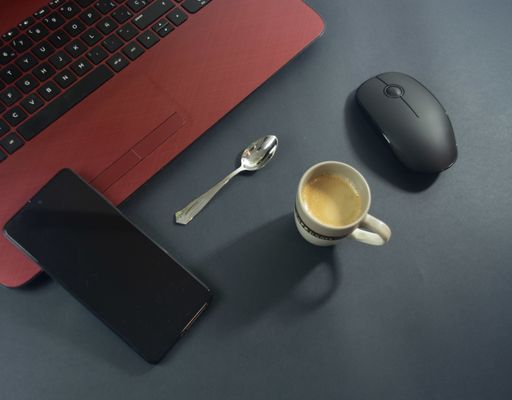 A workplace with telephone, coffee, and keyboard