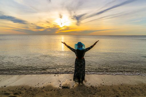 A beautiful view of the ocean in the background and a woman standing with open arms in the foreground