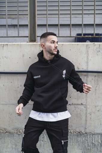 A vertical shot of a young trendy male posing in a black streetwear outfit