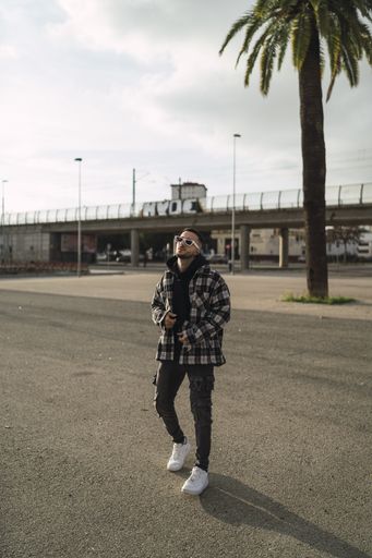 A vertical shot of a handsome stylish male in sunglasses posing in front of the camera