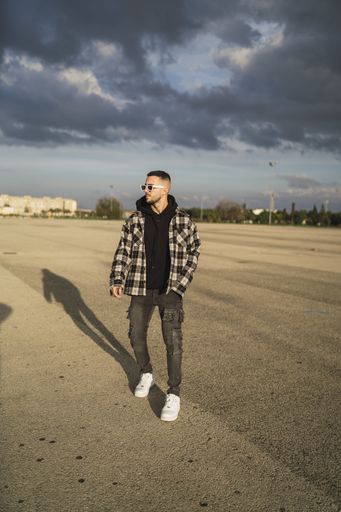 A vertical shot of a handsome stylish male in sunglasses posing in front of the camera