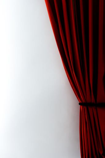 A vertical shot of red curtains with a white wall